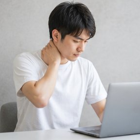 作業中に首のつらさを感じる男性